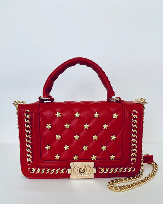 Red handbag with gold chain and star patterns on a white background